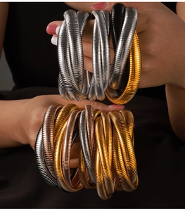 Nahaufnahme elastischer Schlangenknochen-Armbänder in Gold-, Silber- und Roségoldtönen