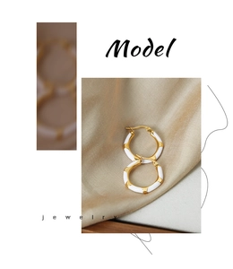 Detail of gold-plated hoop earrings with white enamel zebra pattern on silk background