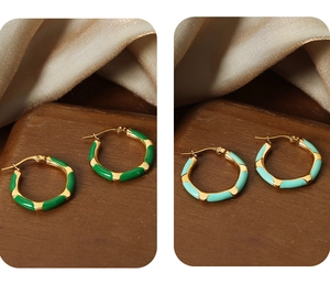 Detail view of colorful enamel hoop earrings in green and light blue with gold texture
