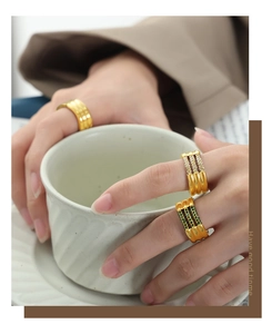Primer plano de anillos dorados vintage con circonitas brillantes y piedras verdes ondeadas