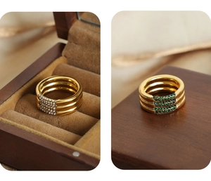 Detalle de anillo dorado de tres filas con incrustaciones de circón verde y blanco