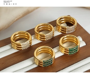 Detalle macro de anillos vintage bañados en oro de 18k con pavé de circonitas verdes y blancas
