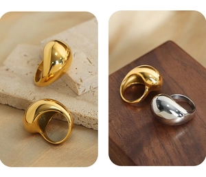 Detailed view of polished gold and silver teardrop rings on stone and wood pedestals
