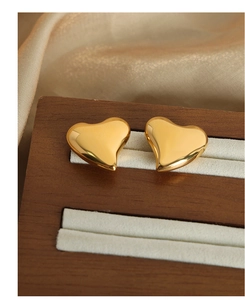 Primer plano de pendientes de corazón en acero dorado con acabado espejo en seda