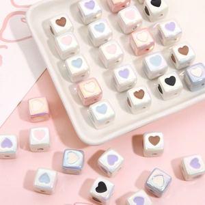 Colorful acrylic heart cube beads for DIY jewelry making on white ceramic tray
