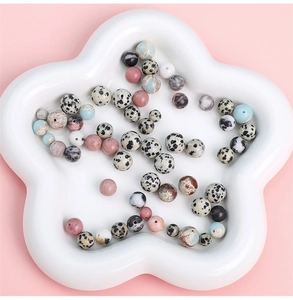 Detailed view of colorful natural stone round beads for DIY jewelry in a white flower tray