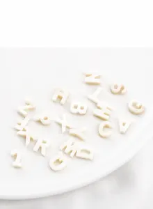 Macro shot of white freshwater shell letter beads in a ceramic tray for DIY jewelry