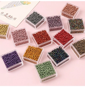 Detailed top view of various colorful glass seed beads in transparent plastic storage boxes