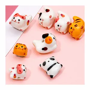 Macro detail of hand-painted ceramic cat and panda beads with transverse holes for DIY jewelry