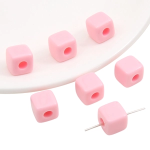 Macro view of solid light pink acrylic cube beads with holes for DIY jewelry making
