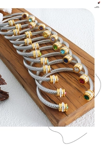 Gros plan de bracelets en câble torsadé avec zircons colorés sur un support en bois