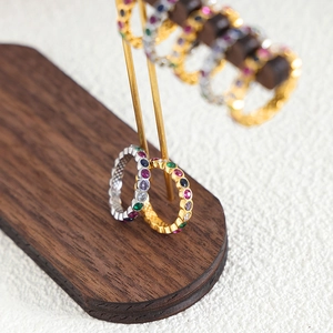 Bohemian eternity rings with colorful zircons in gold and silver finishes on wood stand