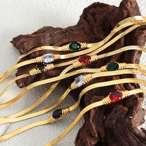 Retro-Gold-Schlangenkette mit bunten ovalen Edelsteinen auf einem rustikalen Holzzweig