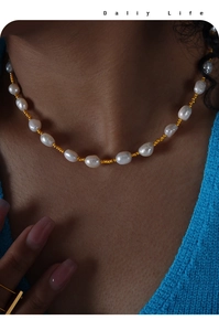 Nahaufnahme der barocken Perlenkette mit Goldperlen an einem Model vor blauem Strick
