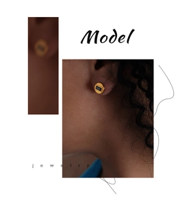 Détail de boucles d'oreilles géométriques dorées avec pierres noires sur un modèle
