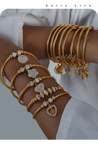 Dettaglio di braccialetti boho dorati a strati con ciondoli a cuore e stella sul polso