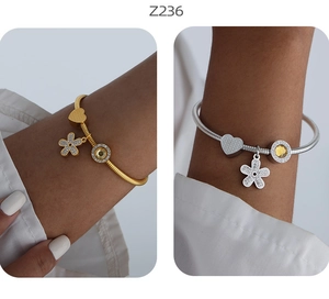 Dettaglio di bracciali a catena serpente oro e argento con ciondoli a fiore, cuore e gemme