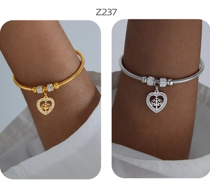 Dettaglio di braccialetti a cuore oro e argento con ciondoli albero della vita e zirconi