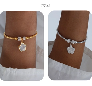 Dettaglio di bracciali con ciondolo a fiore e zirconi scintillanti in oro e argento