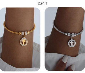 Dettaglio dei bracciali a croce oro e argento con scintillanti pietre incastonate