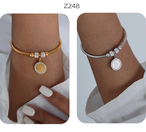 Dettaglio dei bracciali a serpente oro e argento con ciondolo Vergine Maria e zirconi
