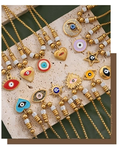 Detailaufnahme von 18K vergoldeten Evil Eye Herzanhängern auf strukturiertem Stein
