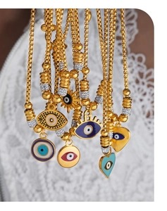 Detail von 18k vergoldeten Halsketten mit bunten Evil Eye Anhängern auf Spitzenhintergrund