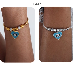 Detailansicht der gold- und silbernen Herz-Augen-Perlenarmbänder am Handgelenk des Models
