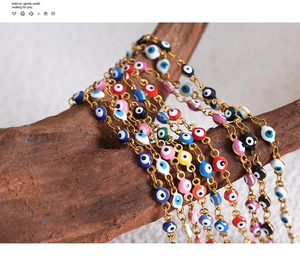 Close-up of colorful evil eye beaded gold chains on natural wooden stand display