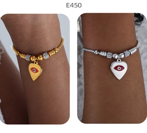 Detail von Herz-Armbändern mit bösem Auge in Gold und Silber am Handgelenk