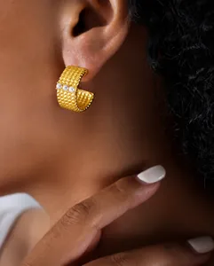 Détail de la boucle d'oreille dorée en titane en forme de C avec texture et trois perles