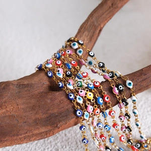 Gold plated evil eye bead bracelet with colorful charms on a natural wooden branch