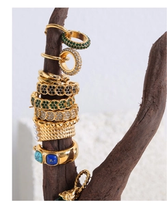 Détail de boucles d'oreilles et bagues dorées avec gemmes vertes et perles sur support