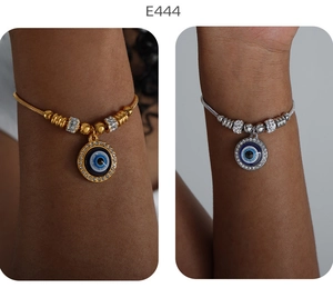 Nahaufnahme goldener und silberner Schlangenarmbänder mit Evil Eye Anhängern