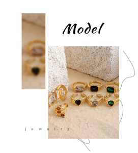 Dettaglio macro di anelli in oro 18k con smeraldi e motivi metallici in rilievo vintage