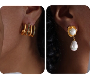Nahaufnahme von goldenem Ear Cuff mit grünen Steinen und edlen Perlenohrringen am Model