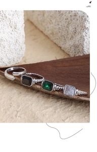 Dettaglio macro di pietre vintage in vetro smeraldo e nero su anelli in acciaio