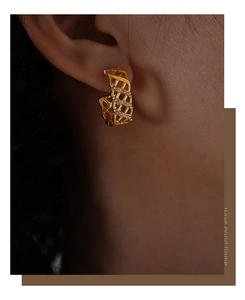 Close-up of gold hollow woven hoop earrings with sparkling white zircon inlays on model