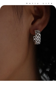 Macro shot of silver-tone hollow braided hoop earring with sparkling zircon inlays