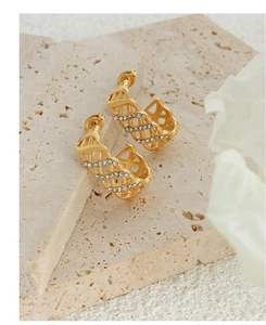 Detail of C-shaped gold-plated hoop earrings featuring intricate mesh texture and rhinestones