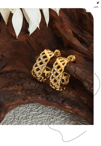 Detail of gold geometric hollow earrings with crystals on a rustic wooden stand