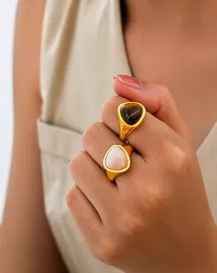 Detail of gold stacked rings with triangular tiger eye and rose quartz on model hand
