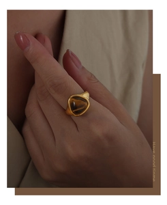 Macro detail of a wide gold-plated titanium ring featuring a natural tiger eye gemstone