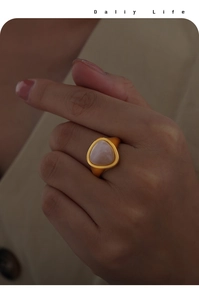Close-up of a gold-plated triangular rose quartz ring worn on a woman's finger