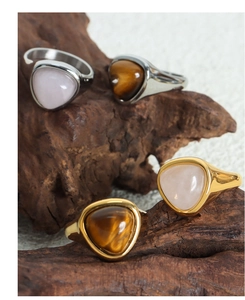 Detail view of gold and silver signet rings with triangular tiger eye stones on wood