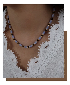 Détail d'un collier bohème en aigue-marine porté sur un haut en dentelle blanche