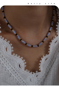 Détail d'un collier bohème avec pierres cylindriques bleues et perles noires sur la clavicule