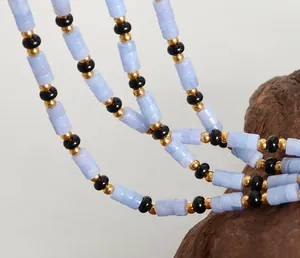 Vue détaillée des pierres d'aigue-marine cylindriques et perles dorées sur le collier