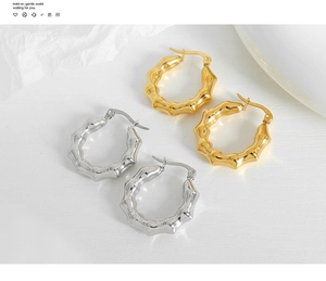 Detalle de pendientes de aro dorados y plateados estilo bambú en fondo minimalista