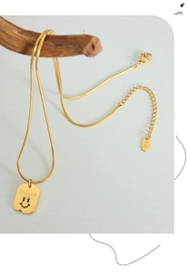 Detail der goldenen Schlangenkette mit Smile-Anhänger und K18-Stempel auf dem Tag